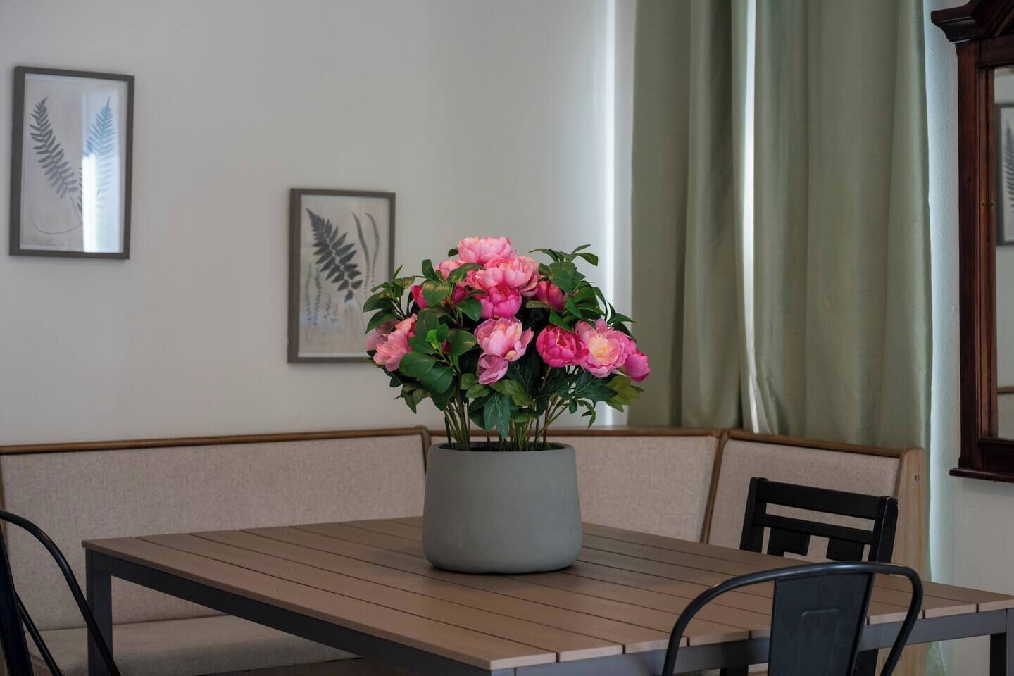 Een eetgedeelte met een tafel, stoelen, een potplant en lijstwerken aan de muur.