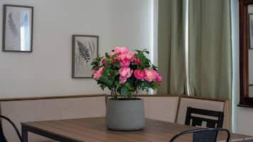 Een eetgedeelte met een tafel, stoelen, een potplant en lijstwerken aan de muur.