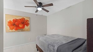 A bedroom with a bed, a ceiling fan, and a wall-mounted painting. - Magnolia House; Grille/Firepit/Patio View! (Tampa)