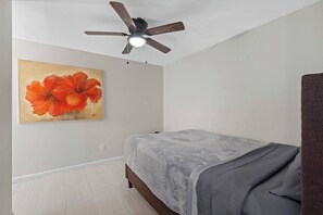 Ein Schlafzimmer mit einem Bett, einem Deckenventilator und einem Wandbild.