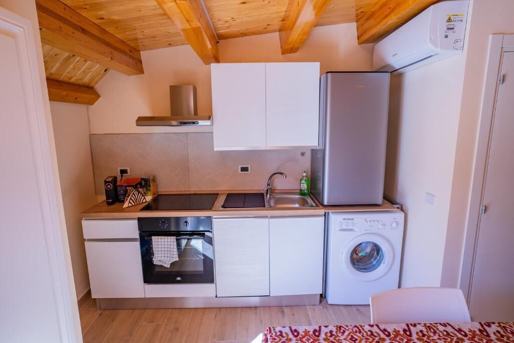 Una cucina compatta con forno a incasso, lavatrice e frigorifero.