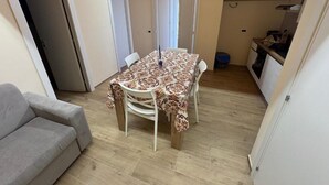 Un espacio habitable compacto con una mesa de comedor, un sofá y una kitchenette.