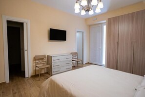 A bedroom with a bed, a dresser, a television, and a wardrobe.