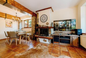 A cozy living room with a fireplace, a dining area, and a television displaying Netflix content.