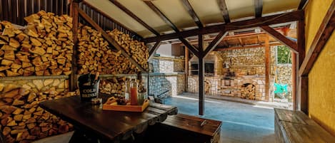A rustic interior with a wooden table, a basket of bread, and a bottle of cold drinks.
