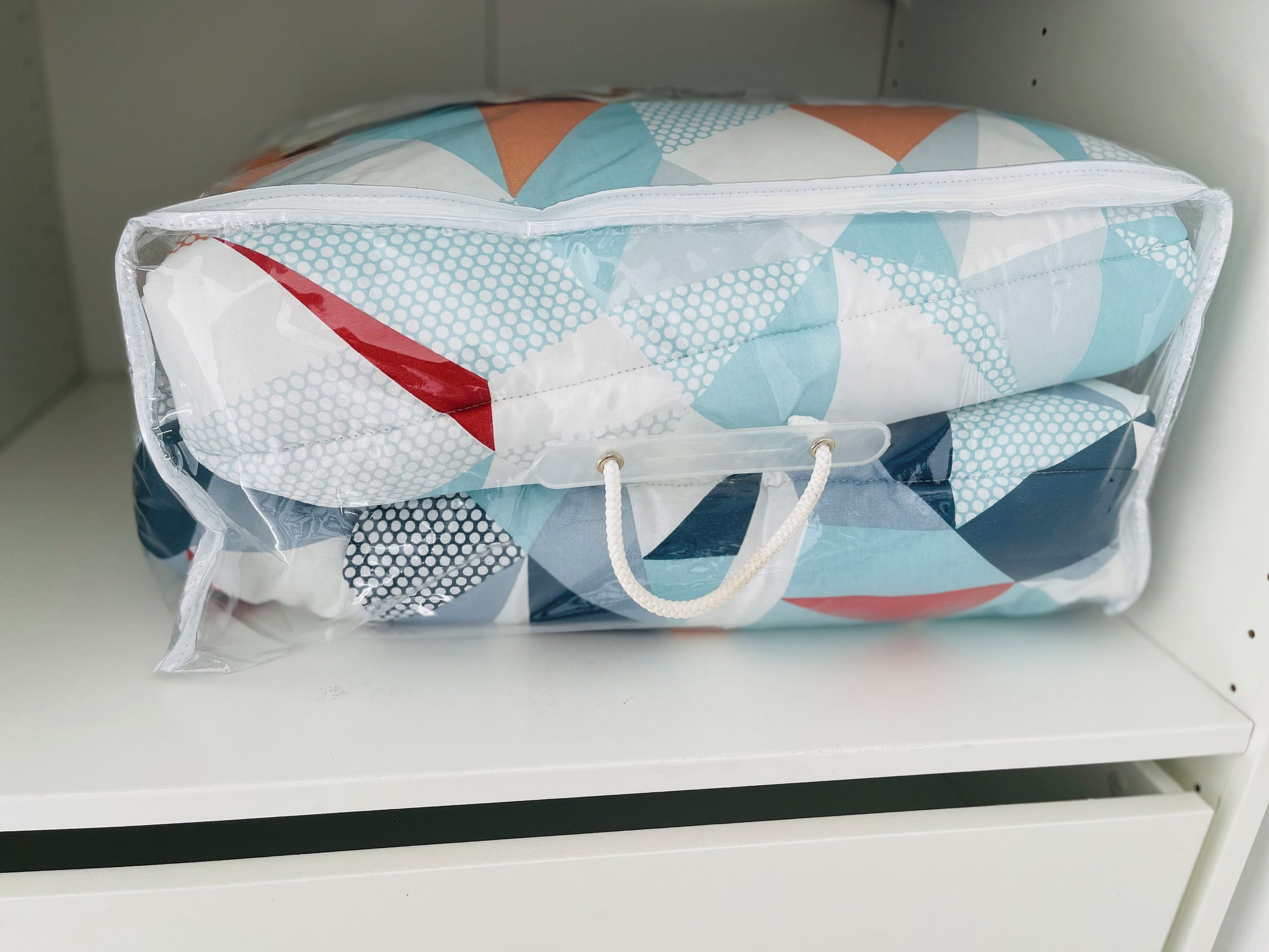 Ein weißer Lagerraum mit einer transparenten Plastiktüte, in der eine gesteppte Tasche mit Henkel steckt.