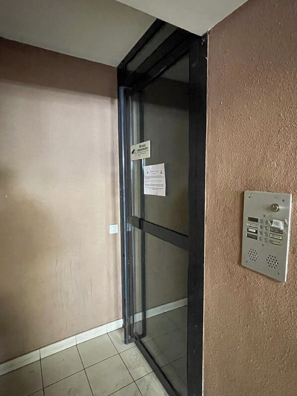 A door with a glass panel, a wall-mounted intercom, and a sign indicating a site-specific water protection area.