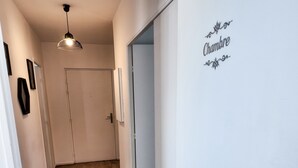 A hallway with wooden flooring, a door, and a wall with a sign that reads 'Chambre.'