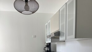 A compact kitchen with a built-in oven, a coffee maker, and a sink.