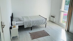 A bedroom with a bed, bedside table, and a window.