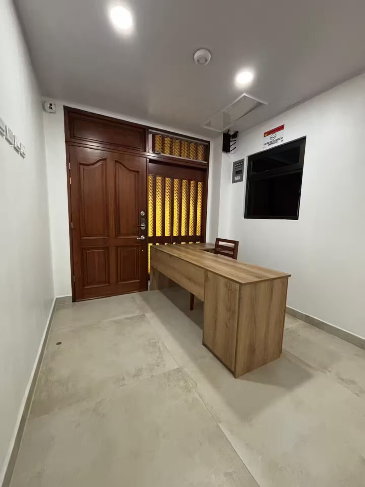 Una habitación con un escritorio de madera, una puerta grande y una ventana.