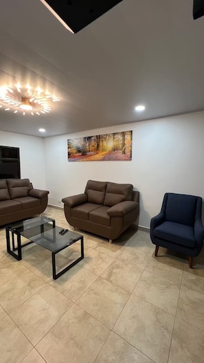 A living room with two brown sofas, a glass coffee table, and a blue armchair.