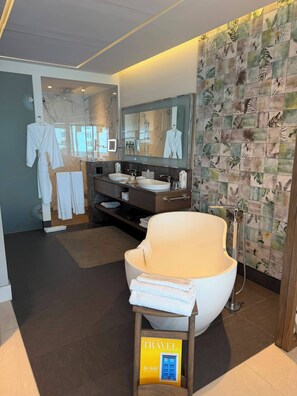 Ein modernes Badezimmer mit großem Spiegel, zwei Waschbecken, einer Dusche und einem Handtuchhalter.