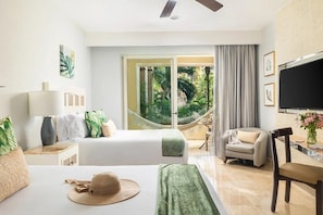 Ein Hotelzimmer mit Bett, Schreibtisch, Sessel, Fernseher und Blick ins Freie.