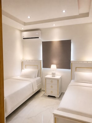 A hotel room with two beds, a bedside table with a lamp, an air conditioning unit, and a window with a view. - Ocean View, 5 min drive to Beach, Hot Water, Elevator, 24/7 Power. (La Romana)