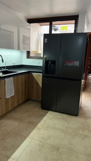 A kitchen with a built-in refrigerator, a sink, and a window with a view of the street. - 102 El Mejor hospedaje en San José cerca al Estadio Nacional -Sabana Norte (San José)