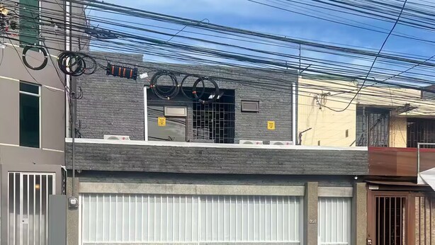 Un edificio a due piani con un'autorimessa e un ingresso chiuso da cancello.