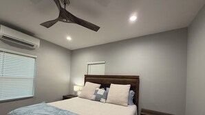 A bedroom with a bed, nightstands, a ceiling fan, an air conditioner, and a window with blinds. - 7 Acre Hidden Hills Cabin 35 minutes from Nashville (Portland)