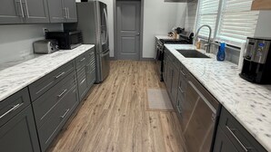 A modern kitchen with grey cabinets, a stainless steel refrigerator, a microwave, and a sink. - 7 Acre Hidden Hills Cabin 35 minutes from Nashville (Portland)