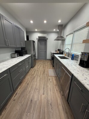 A modern kitchen with grey cabinets, a stainless steel refrigerator, a microwave, and a sink. - 7 Acre Hidden Hills Cabin 35 minutes from Nashville (Portland)