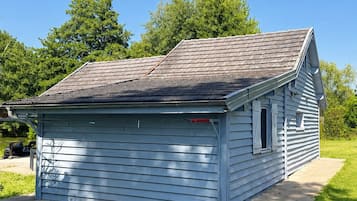 Un petit bâtiment d’un seul étage, doté d’un toit en pente, d’une porte de garage et de fondations en béton.