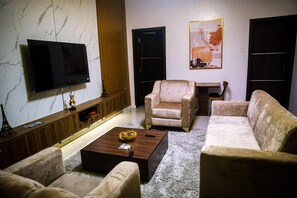 Ein Wohnzimmer mit Flachbildfernseher, zwei Sofas, einem Couchtisch und einem Gemälde an der Wand.