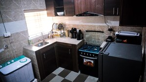 Uma cozinha compacta com fogão a gás, forno embutido, geladeira e pia.