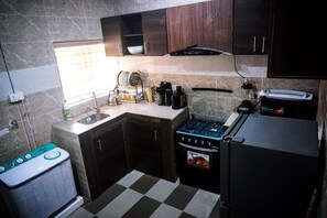 Eine kompakte Küche mit Gasherd, Backofen, Kühlschrank und Spüle.