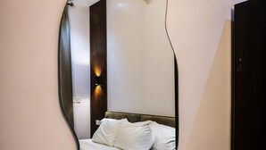 Quarto com cama, espelho na parede e mesa de cabeceira.