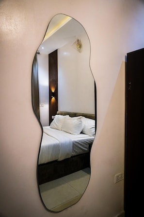 Ein Schlafzimmer mit einem Bett, einem Wandspiegel und einem Nachttisch.