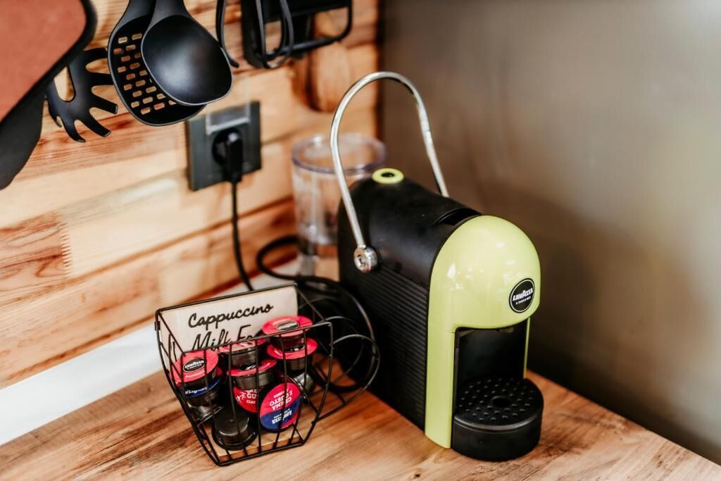 A coffee machine with a milk frother and a coffee grinder on a wooden surface.