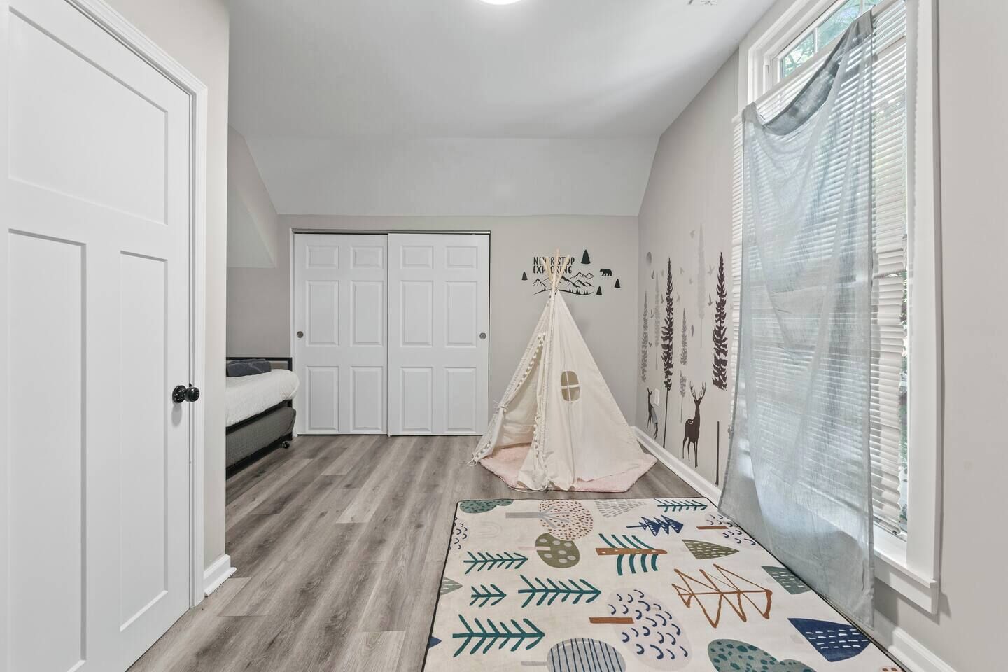 Une chambre à coucher avec un lit, une armoire, une fenêtre avec des stores et une structure en forme de tente dans un coin.