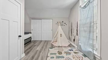 Une chambre à coucher avec un lit, une armoire, une fenêtre avec des stores et une structure en forme de tente dans un coin.