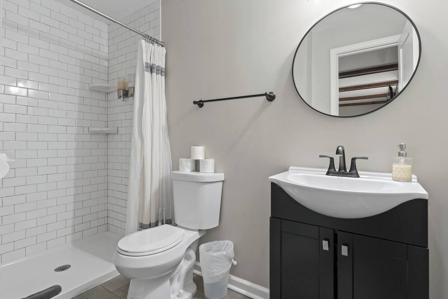 A bathroom with a white toilet, a shower with a glass door, a sink with a mirror above it, and a towel rack.