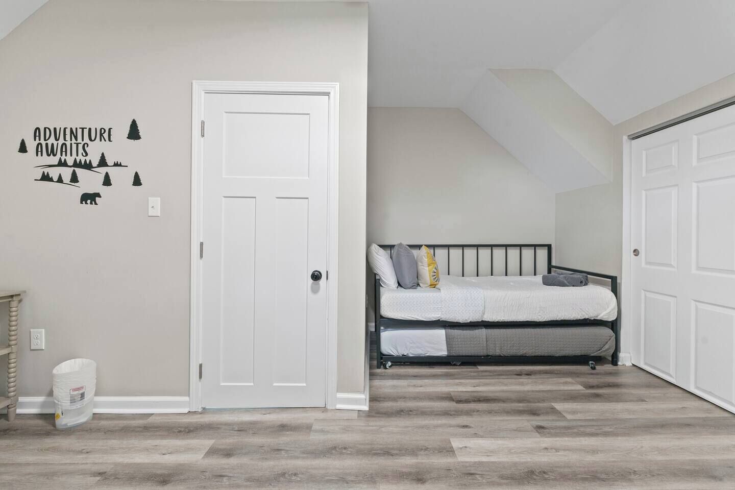 Een slaapkamer met een bed, een witte deur en een muurstickers.