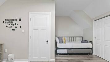 Een slaapkamer met een bed, een witte deur en een muurstickers.