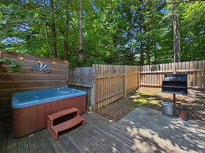Un jardin avec un jacuzzi, une terrasse en bois et une clôture en bois.