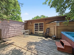 A wooden deck with a hot tub, a table with chairs, and a sliding glass door. - Sleeps 4, Romantic Chalet, Private Hot Tub, Jacuzzi Tub, Gas Fireplace (Gatlinburg)