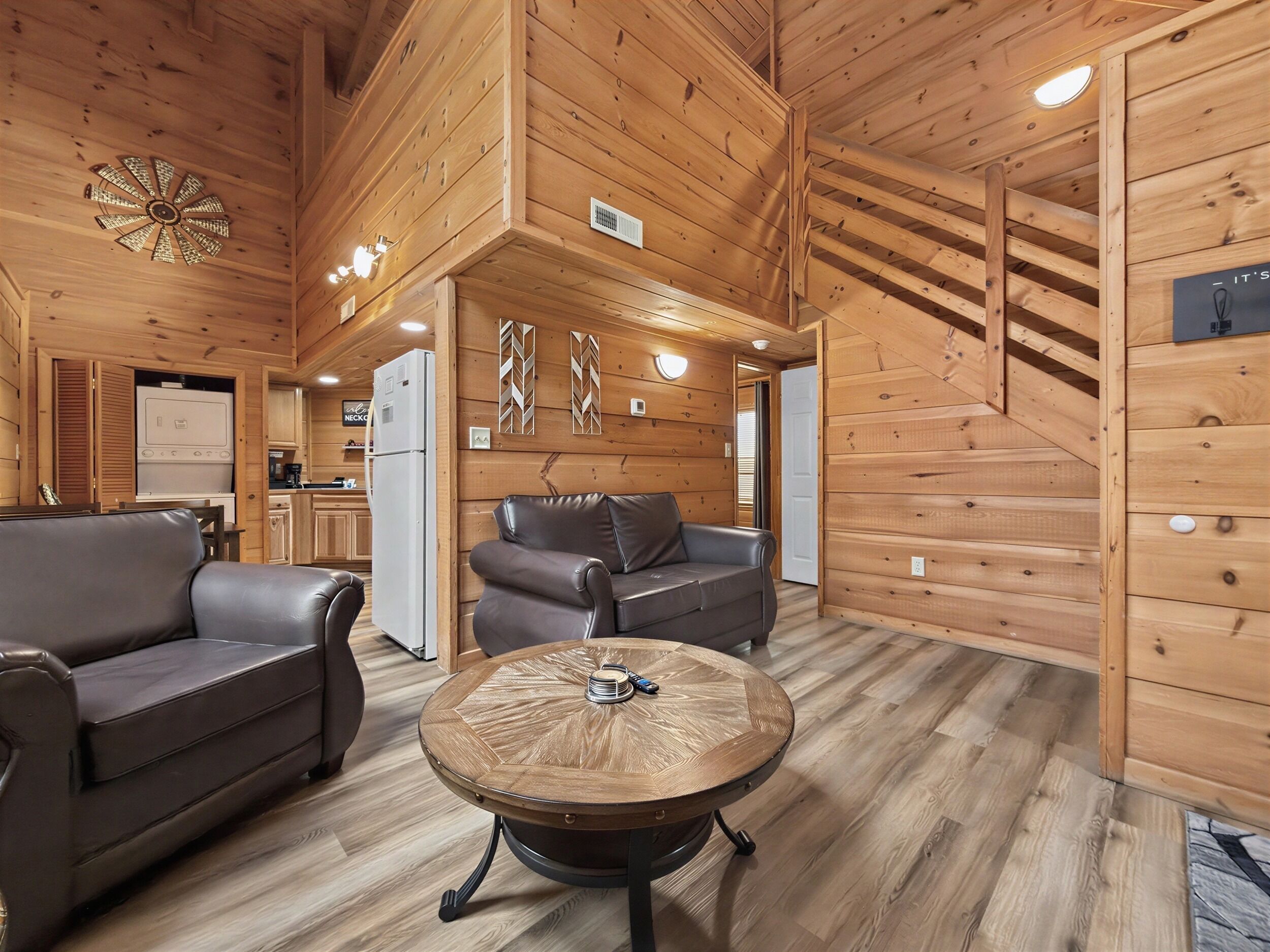 A cabin interior with a dining area, a kitchen, and a living room with a fireplace.