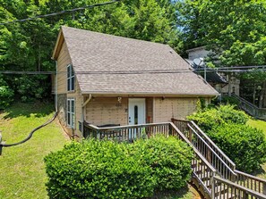 Une maison en bois à deux étages, dotée d’un porche et d’un escalier menant à l’entrée.