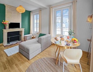 Ein Wohnzimmer mit Kamin, Sofa, Esstisch und Fernseher.