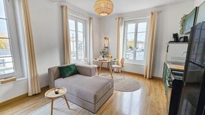 Ett modernt vardagsrum med en soffa, ett runt bord och en hängande lampa.
