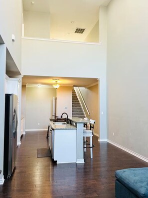 A kitchen with a central island, a refrigerator, and a dining area with chairs. - Modern home: easy airport access & near amenities (Odessa)