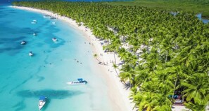A beach with clear turquoise waters, a row of palm trees, and several boats. - ANYA 2 Cozy Tropical Escape Walk to Bayahibe Beach (San Rafael del Yuma)