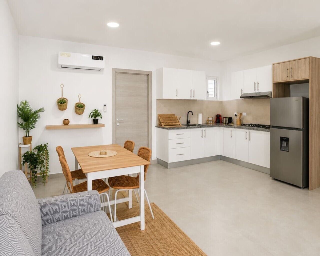 Una cocina moderna con armarios blancos, una mesa de comedor de madera y una estufa integrada.