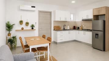 Una cocina moderna con armarios blancos, una mesa de comedor de madera y una estufa integrada.