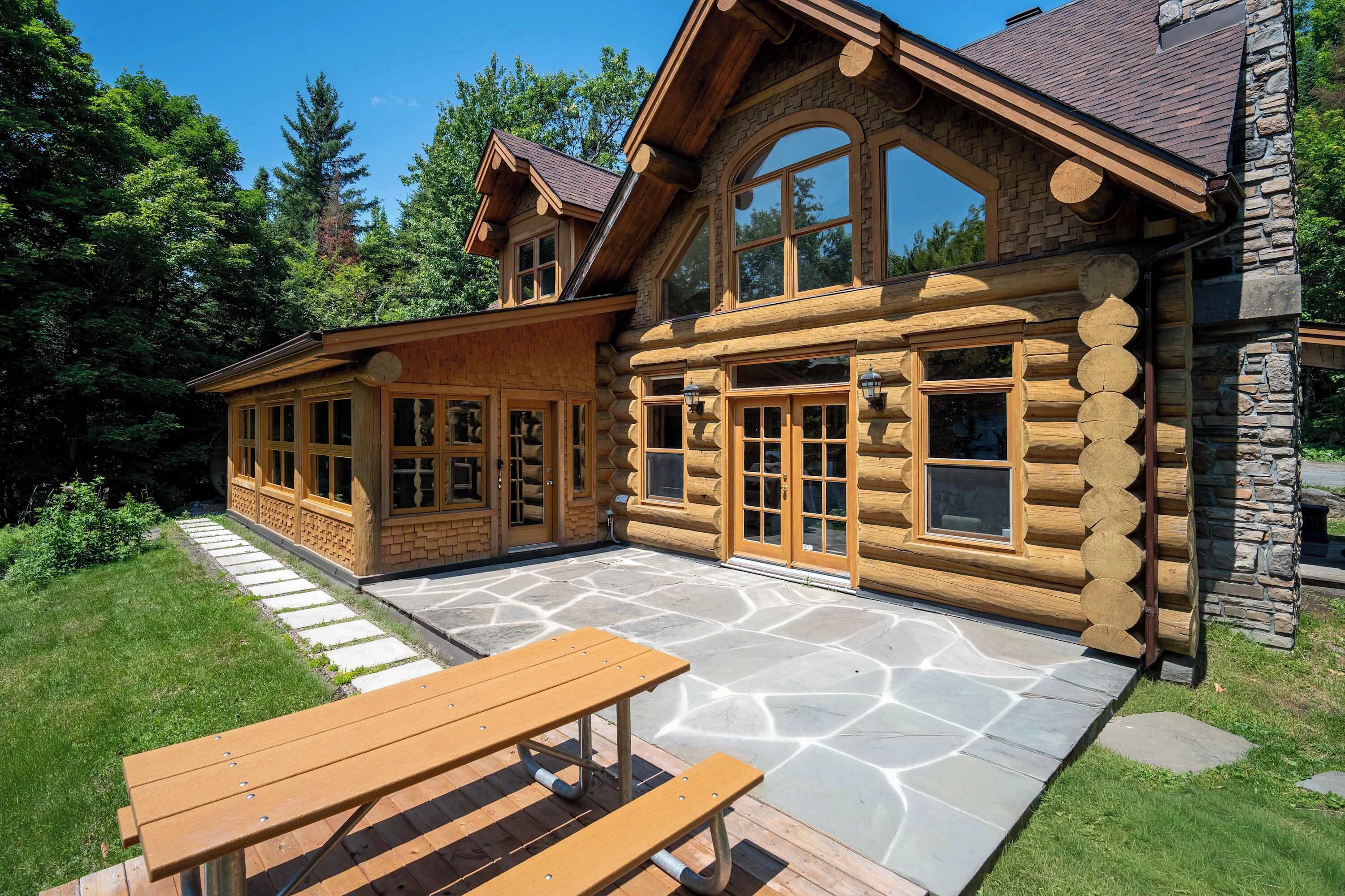 Une cabane en rondins avec un patio en pierre et une table de pique-nique.