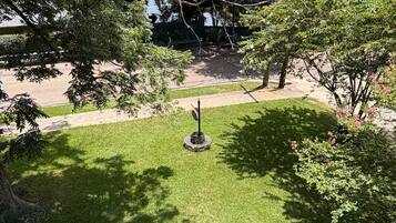 Un césped con una escultura de metal, árboles y una línea de electricidad al fondo.