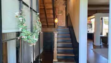 Un pasillo con un tapete de cuadros, escaleras de madera y una escalera que sube a otro nivel.