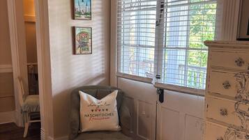 A room with a single green upholstered bench, a white dresser with ornate handles, and two framed pictures on the wall.
